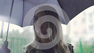 a young European girl stands with a black umbrella