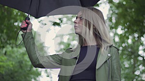 young european girl walks with a black umbrella