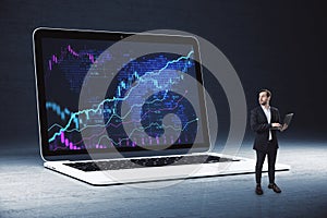 Young european male looking at huge laptop with forex chart on screen. Trade, finance and money concept