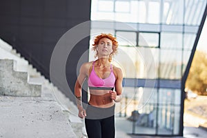 Young european redhead woman in sportive clothes running outdoors