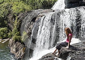 Young european tourist girl sitting on the edge of the Baker`s falls in the national park