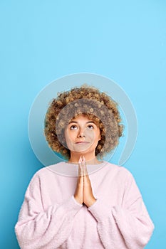 Young European woman, 30s years old wears beige sweater, hands folded in prayer gesture begging about something with