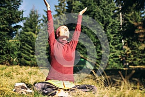 Young european woman doing yoga on the grass in autumn forest.