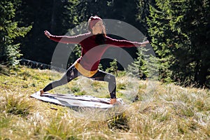 Young european woman doing yoga on the grass in autumn forest.