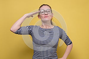 Young european woman with glasses saluting showing her patriotism