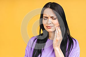 Young European woman isolated over yellow background suffering from severe toothache, feeling pain so strong that she is pressing