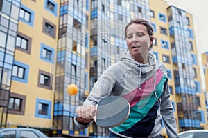 Young european woman playing table tennis in yard