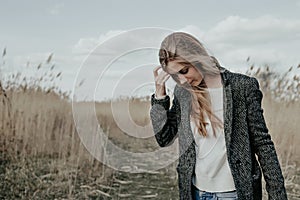 Young european woman walking on country road through bulrush