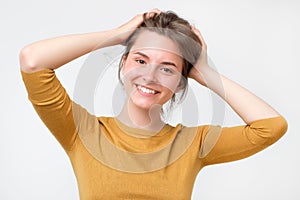 Young european woman in yellow sweater with beautiful smile in studio. Portrait on gray background.