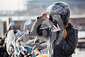 Young girl biker trying black motorcycle helmet for ride on bike photo