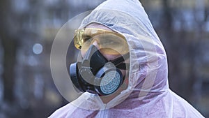 The young europeans man in protective chemical suit and respirator, outdoors. New coronavirus COVID-19