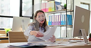 Young excited cheerful woman businesswoman throwing papers celebrating business success in office