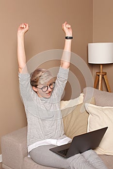 Young excited female celebrating her achievments and wins with her hands up, looking in notebook