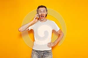 young excited man in casual clothes with phone in his hand with his mouth open with happiness. I received happy news