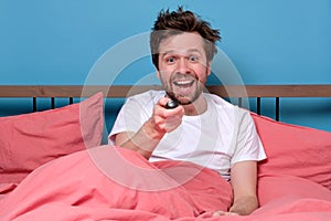 Young excited man watching tv or movies and excite while using remote control