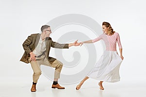 Young excited man and woman in 60s american fashion style clothes dancing retro dance isolated on white background