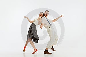 Young excited man and woman in 60s american fashion style clothes dancing retro dance  on white background