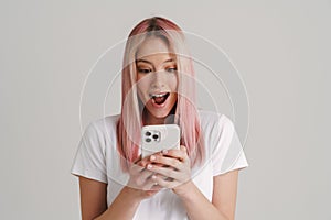 Young excited woman exclaiming while using mobile phone