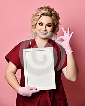 Young excited woman holding empty blank board smiling show ok sign on pink