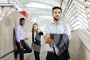 Young executive business standing with arms crossed and background  employee are bullying him