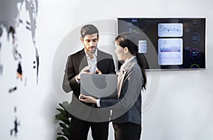 A young executive and a female employee stand and look at a notebook. for online business meetings of the company