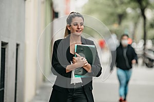 Young executive woman goes to office to work walking down a street