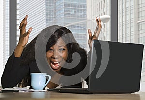 Young exhausted and depressed black African American business woman working upset and sad at office computer desk by the window in