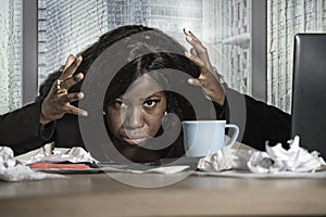 Young exhausted and depressed black African American businesswoman working upset and sad at office computer desk by the window in