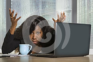 Young exhausted and depressed black afro American businesswoman working upset and sad at office computer desk by the window in cen