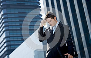 Young exhausted and worried businessman standing outdoors in stress and depression