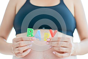 Young expectant mother with letter blocks spelling baby on her pregnant belly