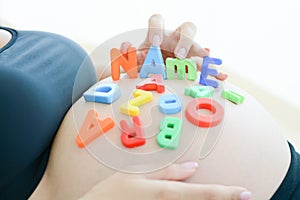 Young expectant mother with letter blocks spelling name on her belly