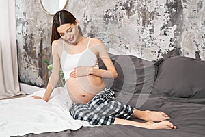 Young expectant woman enjoying her motherhood in bed