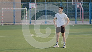 Young experienced coach Indian guy in summer sportswear standing on football field of school stadium prepares for