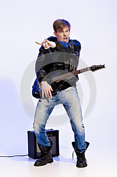 Young expressive rock musician playing electric guitar and singing. Rock star making rock gesture