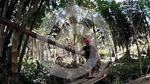 Young fair lady crosses bamboo bridge over spring river replete with natural vegetation