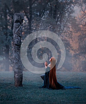 Young fairy came to worship the great old sacred stone, dressed in an amazing velvet blue cloak-dress, kneeling in the
