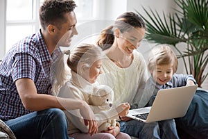 Young family with adopted children using laptop together at home