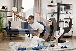 Young family african man and muslim arabic woman practising yoga stretching workout at home