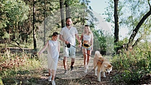 Young family with Akita Inu walking together in the forest