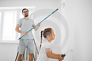 Young family of attractive father and cute little daughter having fun together while repairing room.