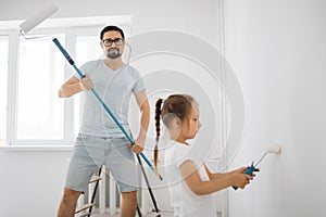 Young family of attractive father and cute little daughter having fun together while repairing room.