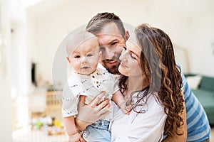 Young family with a baby boy at home, standing and posing for the photo.