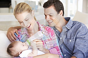 Young Family With Baby Feeding On Sofa At Home photo