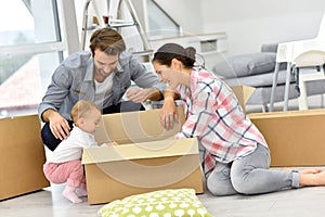 Young family with baby unpacking boxes moving into new house