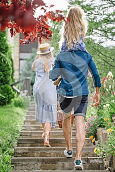 Young family with basket after picnic walking down stairs outside in green park