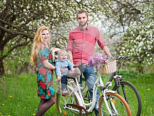 Young family on a bicycles in the spring garden