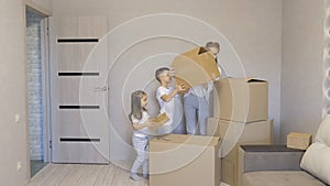 A young family carrying a cardboard box to a new modern house in the living room.The children, a boy and a girl