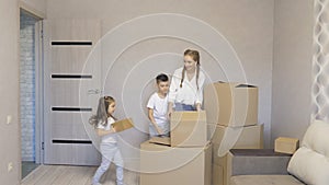 A young family carrying a cardboard box to a new modern house in the living room.The children, a boy and a girl