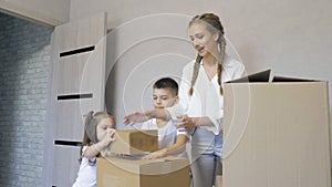 A young family carrying a cardboard box to a new modern house in the living room.The children, a boy and a girl